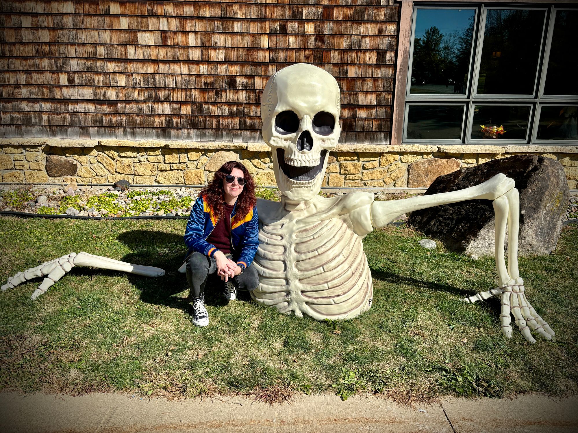 Me, a white woman with long, wavy, dark red hair, kneeling next to a giant skeleton torso coming out of the ground